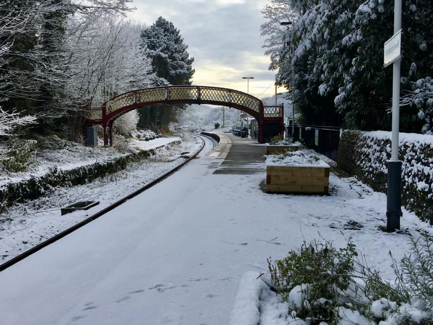 Lightly dusted snowy platform with ornate footbridge Whatstandwell Station