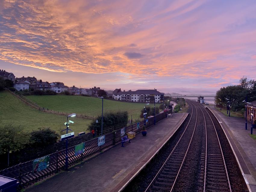 Red sky sunset looking out over the train tracks and platforms of Arnside Station