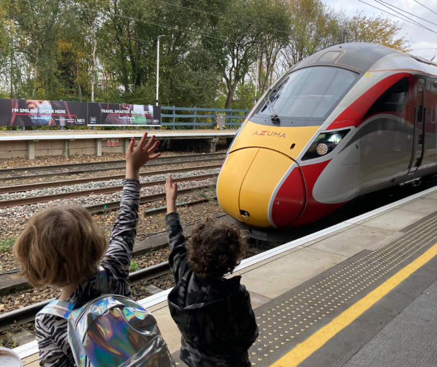 Family waving at train, before going on days out by rail