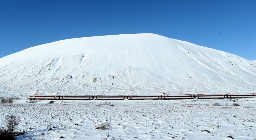 Mountain with snow on, train in the foreground
