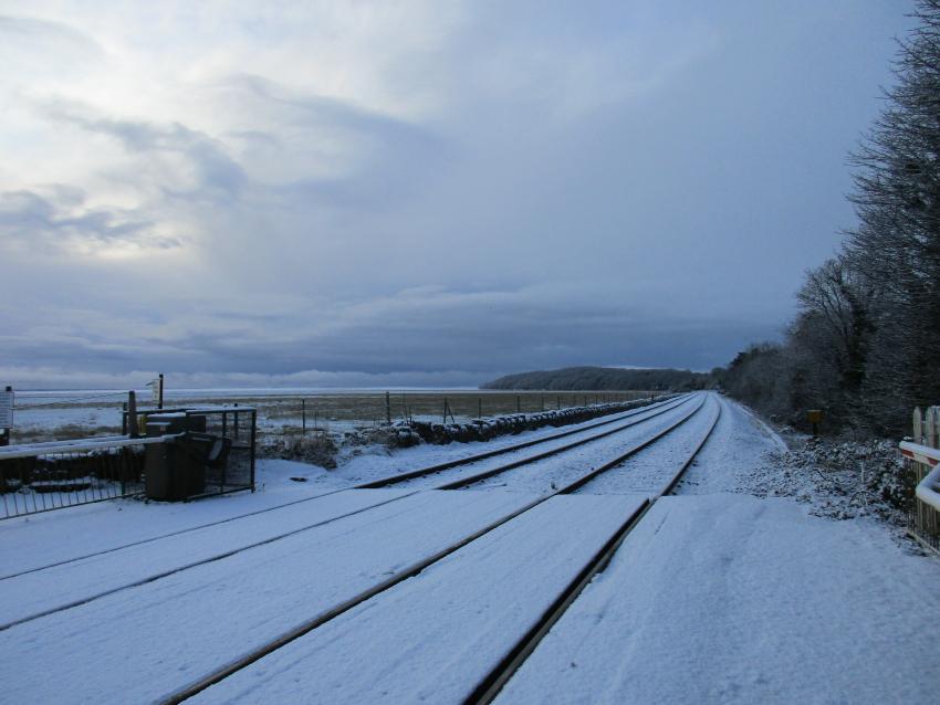Snowy railway at Kents Bank Station with Lake District fells in the background