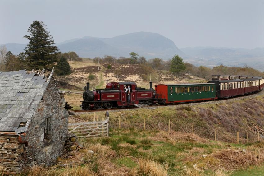 Heritage train travelling through countryside with mountains in background
