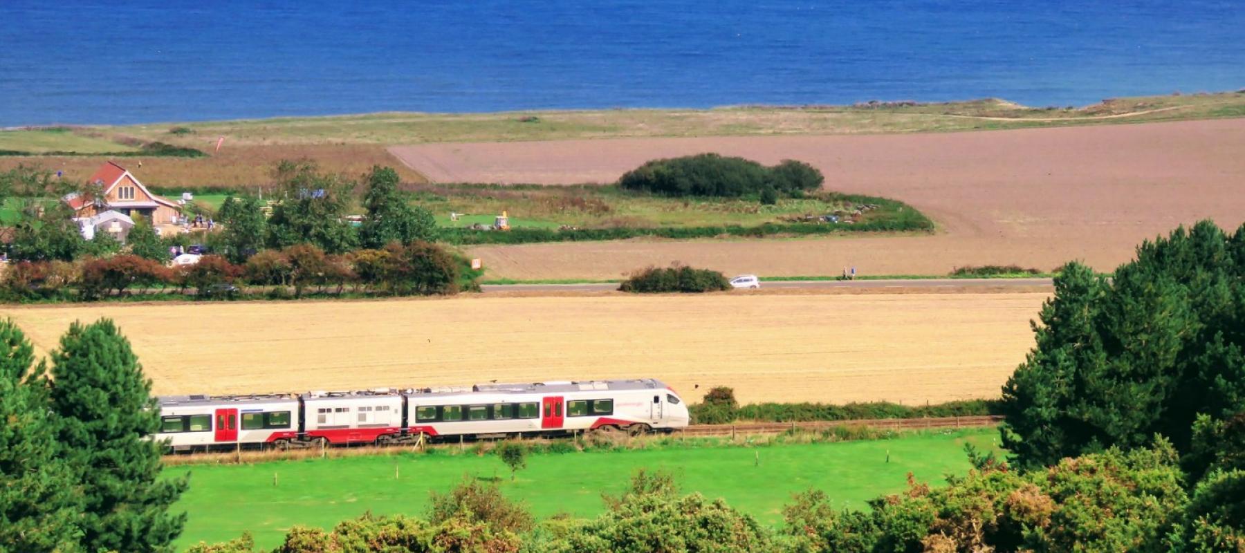 Train travelling along the coast passing West Runton on the Bittern Line