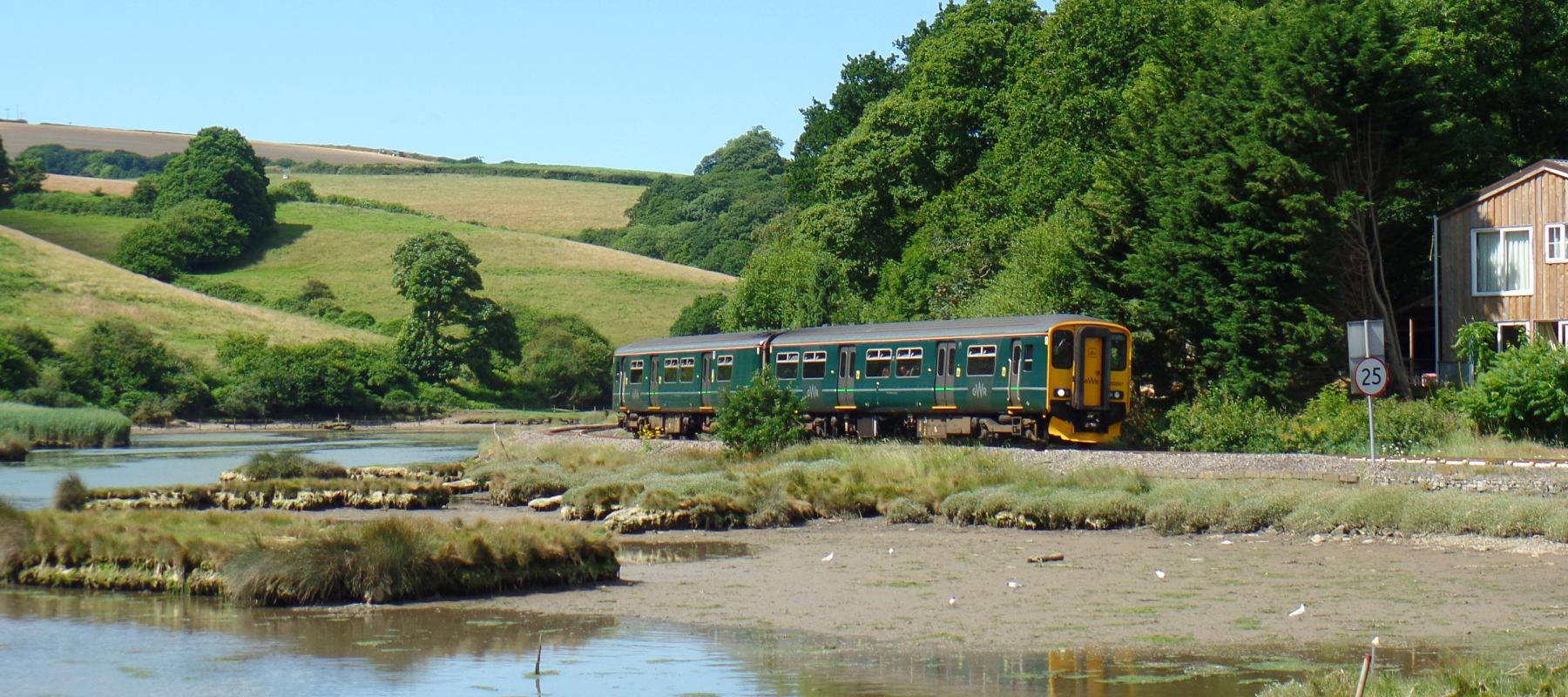 Train running alongside the estuary on the Looe Valley Line