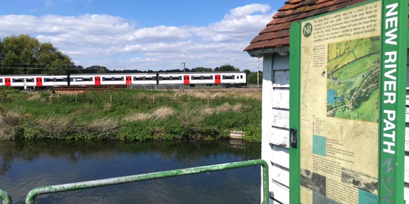 A train to London running alongside the New River Path near Hertford East