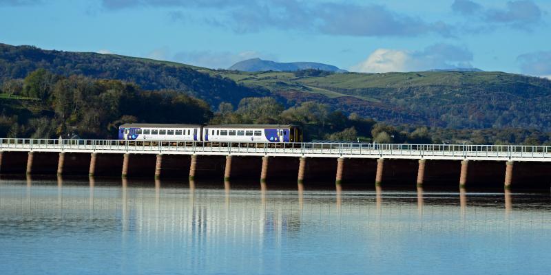 Train travelling over viaduct with Lake District fells in the background