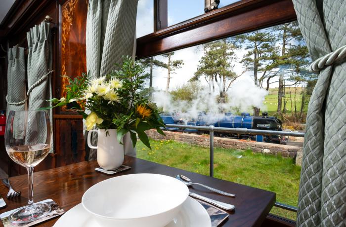 View from converted train carriage of a steam train passing by